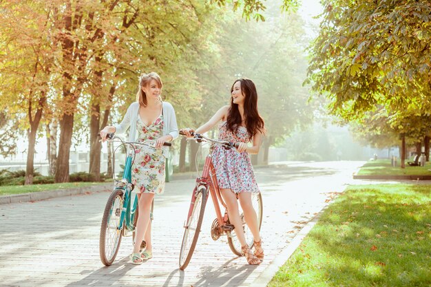 Две молодые девушки с велосипедами в парке