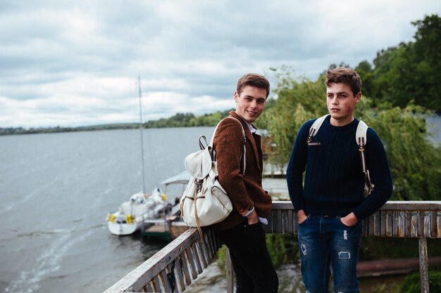 Two young guys stand on the pier and one of them turned his head