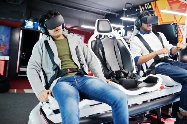 Two young indian people having fun with a new technology of a vr headset at virtual reality simulator