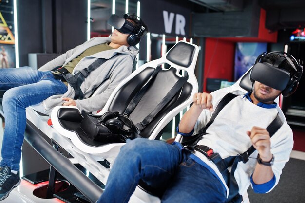 Two young indian people having fun with a new technology of a vr headset at virtual reality simulator