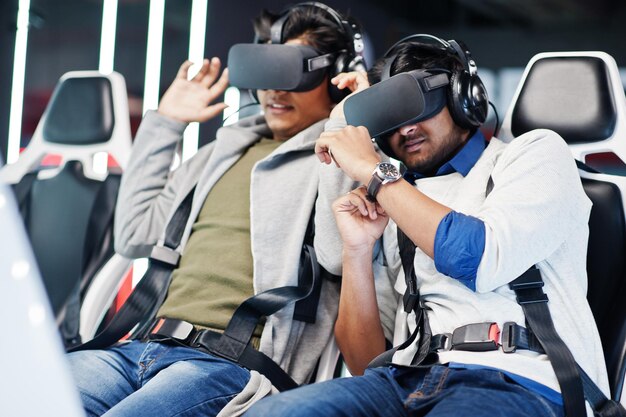 Two young indian people having fun with a new technology of a vr headset at virtual reality simulator