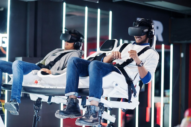 Two young indian people having fun with a new technology of a vr headset at virtual reality simulator