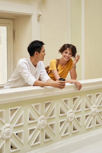 Двое молодых радостных иностранных студентов радостно разговаривают на перемене в коридоре университета