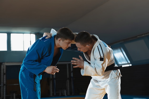 Two young judo fighters in kimono training martial arts in the gym