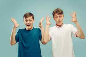 Free photo two young men standing in sportwear isolated on blue