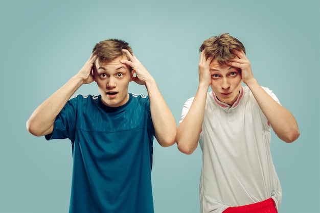 Two young men standing in sportwear isolated. Fans of sport, football or soccer club or team. Friends' half-length portrait. Concept of human emotions, facial expression.