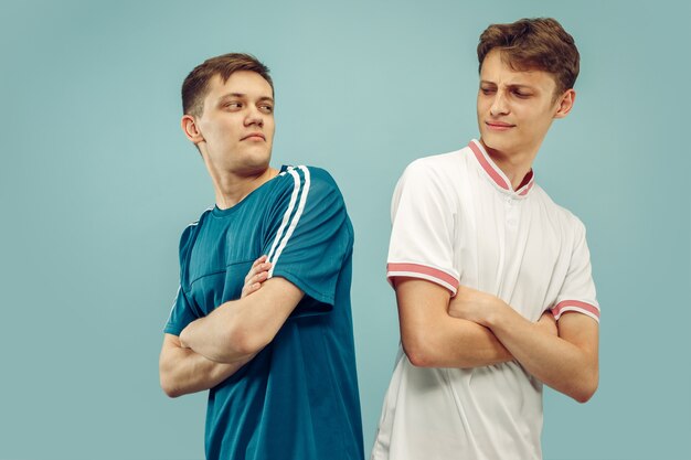 Two young men standing in sportwear isolated. Fans of sport, football or soccer club or team. Friends' half-length portrait. Concept of human emotions, facial expression.