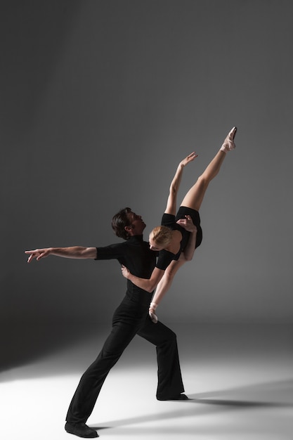 Two young modern ballet dancers on gray  wall