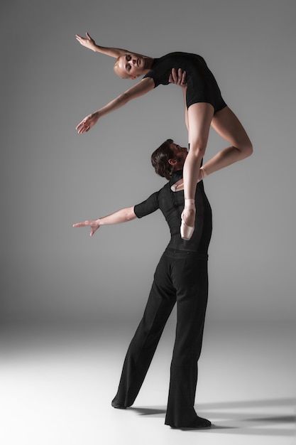 Free photo two young modern ballet dancers on gray