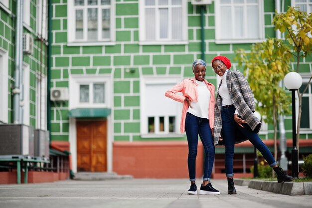 Two young modern fashionable attractive tall and slim african muslim womans in hijab or turban head scarf and coat posed