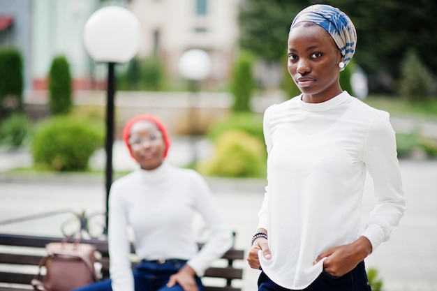 Due giovani donne musulmane africane attraenti moderne alla moda alte e magre in hijab o sciarpa a turbante poste insieme