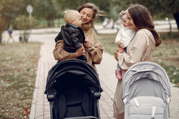 Two young mothers walking in a autumn park with carriages