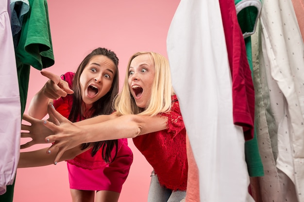 Foto gratuita le due giovani belle ragazze che guardano i vestiti e provano mentre scelgono in negozio