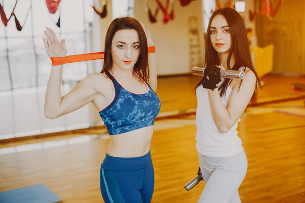 две молодые и красивые девушки в спортивном костюме, занимающиеся спортом в спортзале