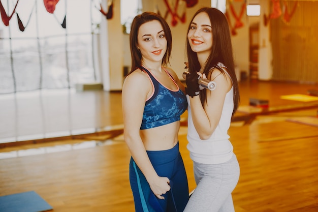 two young and pretty girls in a sports suit engaged in sports in the gym