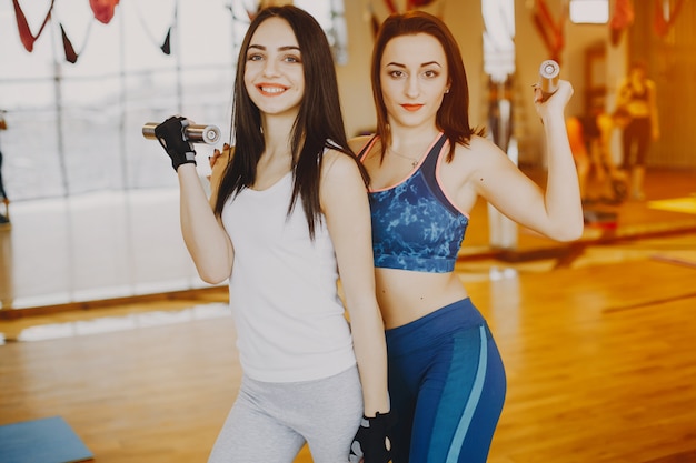 two young and pretty girls in a sports suit engaged in sports in the gym