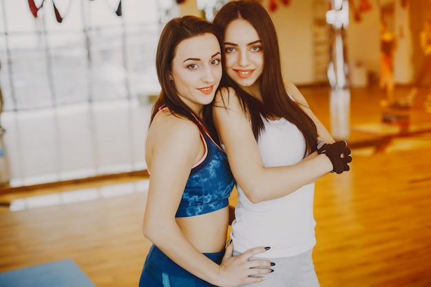 Free photo two young and pretty girls in a sports suit engaged in sports in the gym