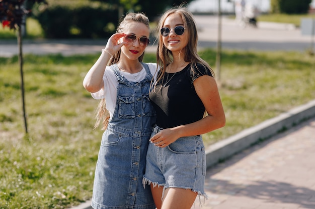 Due giovani belle ragazze in una passeggiata nel parco. una giornata di sole estivo, gioia e amicizie.