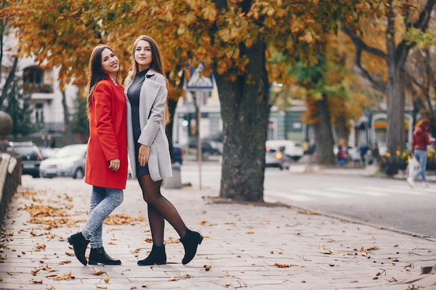 two young and pretty girls walking in a autumn city