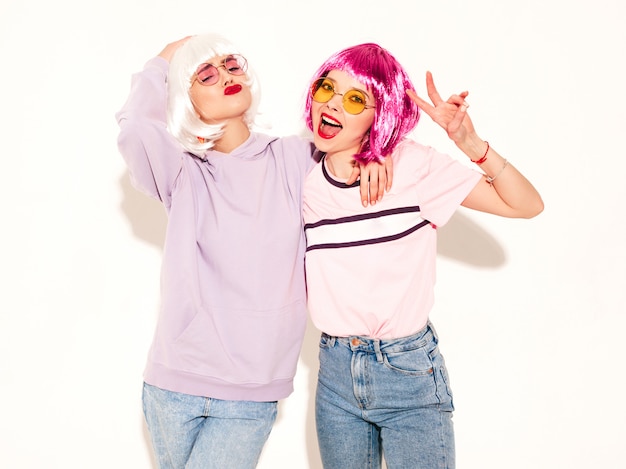 Due giovani ragazze sexy hipster in parrucche e labbra rosse. belle donne alla moda in abiti estivi in occhiali da sole