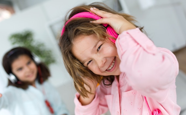 Two young sisters listening to music and dancing at home.