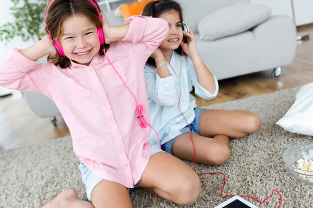 Two young sisters listening to music and dancing at home.