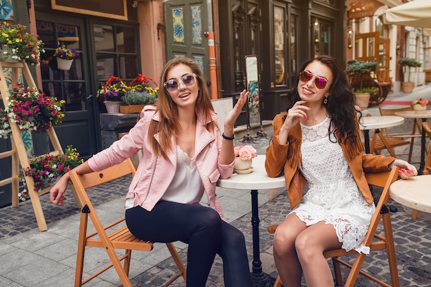 Две молодые стильные женщины, сидя в кафе
