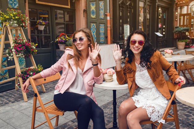 Two young stylish women sitting at cafe