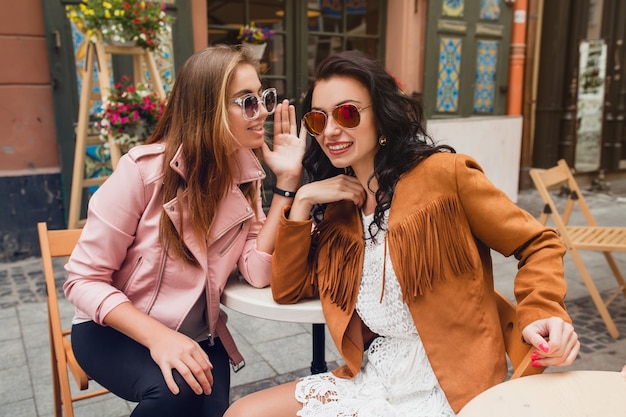Две молодые стильные женщины, сидя в кафе