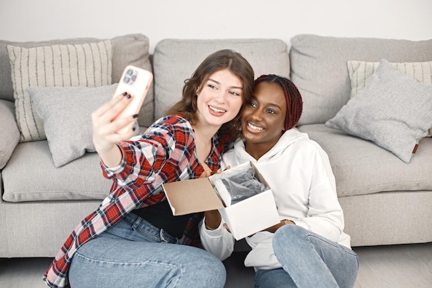 Two young teenage girl sitting on a floor near coach and make a selfie