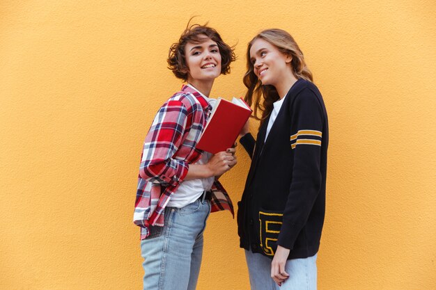 Free photo two young teenage girls with books outdoors