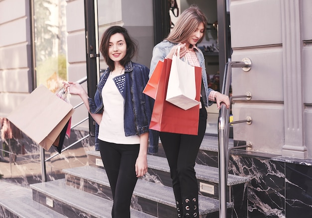 Two young woman carrying shopping bags while walking on the stairs after visiting the stores.