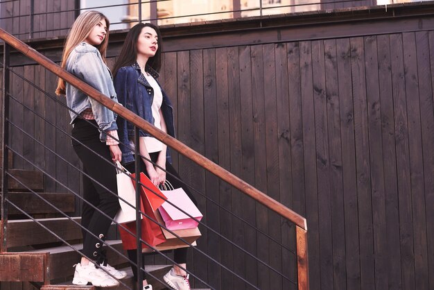 상점을 방문한 후 계단을 걷는 동안 쇼핑 가방을 들고 두 젊은 여자.