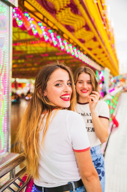 Two young woman standing in front of amusement park