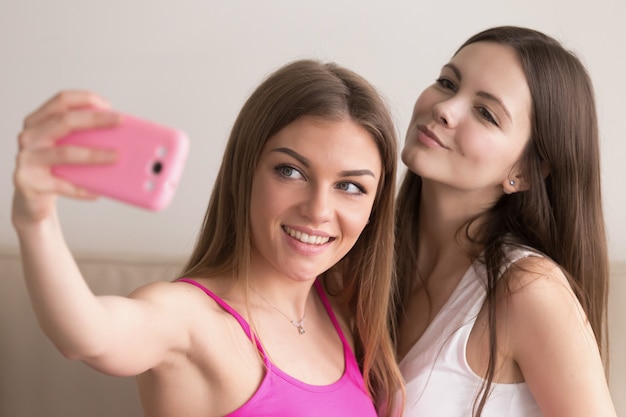 Two young woman take selfie photos with cellphone