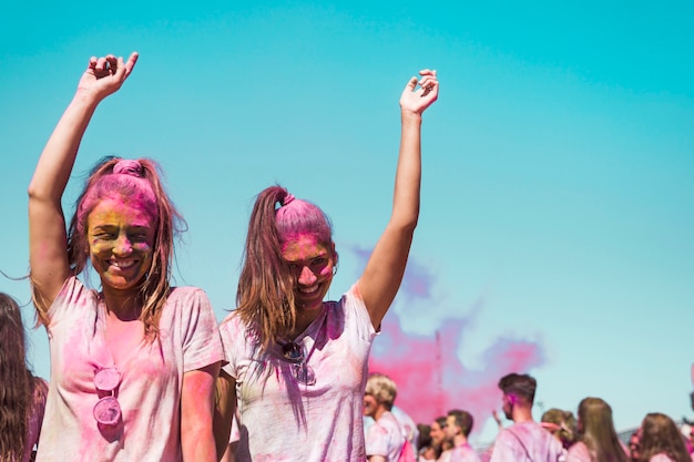 Free photo two young women covered with holi color dancing in the holi festival