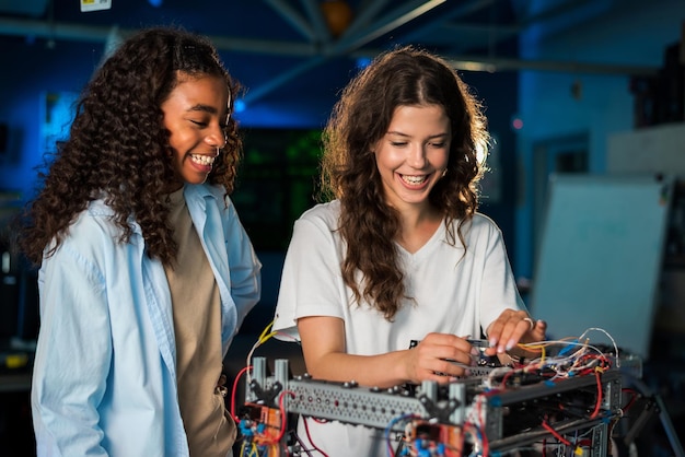 Free photo two young women doing experiments in robotics in a laboratory robot on the table