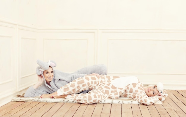 Two young women in a pajamas laying on the floor.