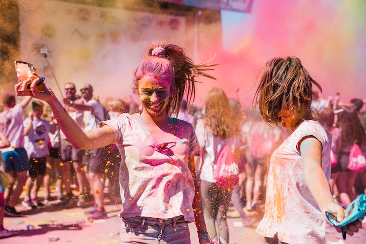 Free Photo two young women playing and enjoying with holi colors