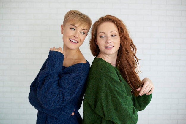 Two young women standing back to back