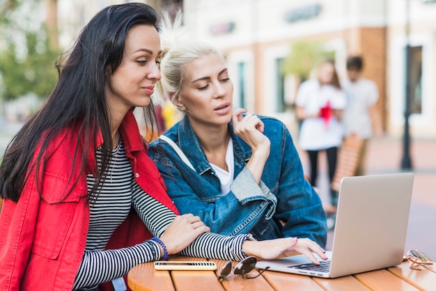 Two young women working on laptop over wooden desk