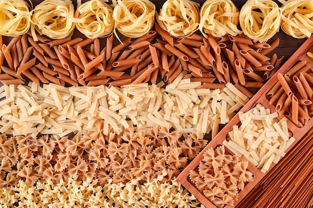 types of raw pasta penne fusilli tagliatelle spaghetti top view