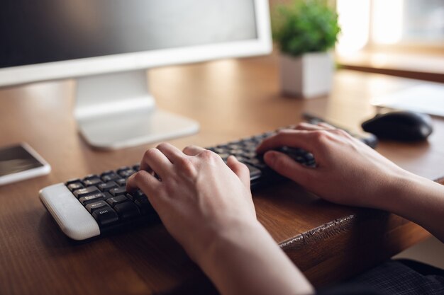 Typing text, close up. Caucasian young woman in business attire working in office