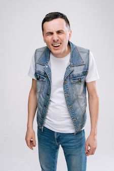 Ufa, russia - 31 march 2020. handsome young man with in denim clothes raising hands in frustrated gesture feeling unsure in something, standing over white isolated background.