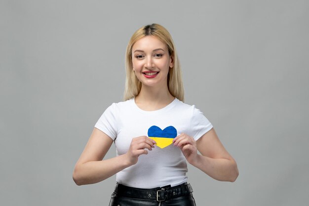 Ukraine russian conflict blonde cute girl holding ukrainian heart happy