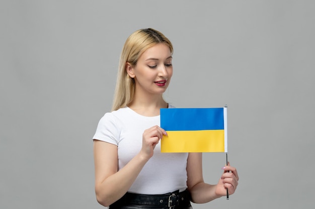 Ukraine russian conflict blonde cute girl with red lipstick and ukrainian flag looking at flag