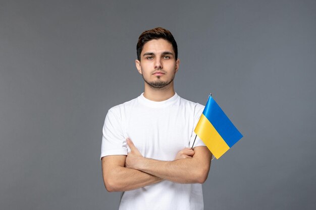 Ukraine russian conflict brave cute handsome guy in white shirt with crossing hands with flag