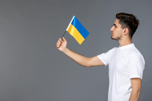ウクライナのロシアの紛争は、ウクライナの旗を掲げて白いシャツを着た勇敢なかわいいハンサムな男