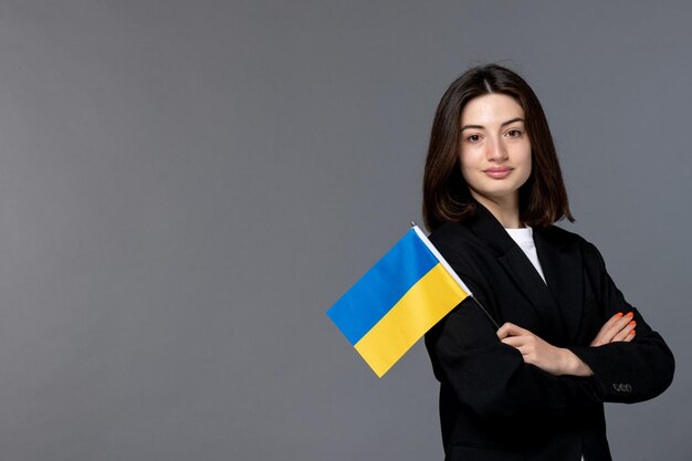 Украинская русская конфликтная брюнетка довольно милая девушка в черном пиджаке скрестила руки с флагом