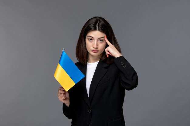 Ukraine russian conflict brunette pretty cute girl in black blazer thinking with ukrainian flag